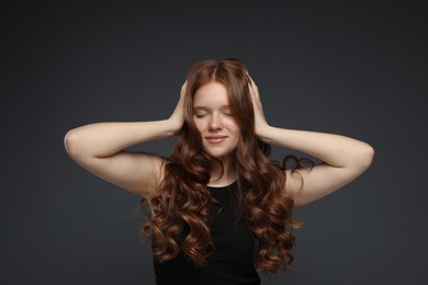 Photo of Beautiful teenage girl with healthy wavy hair on dark grey background