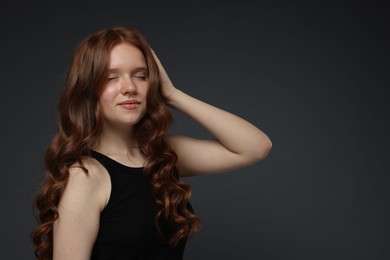 Photo of Beautiful teenage girl with healthy wavy hair on dark grey background. Space for text