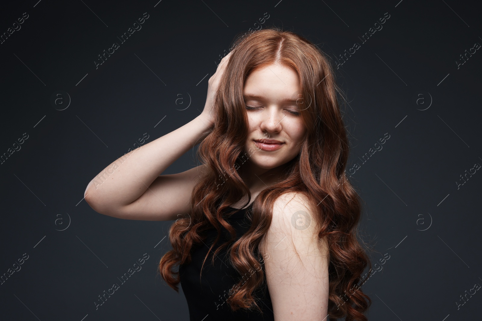 Beautiful teenage girl with healthy wavy hair on dark grey background Photo of Beautiful teenage girl with healthy wavy hair on dark grey background