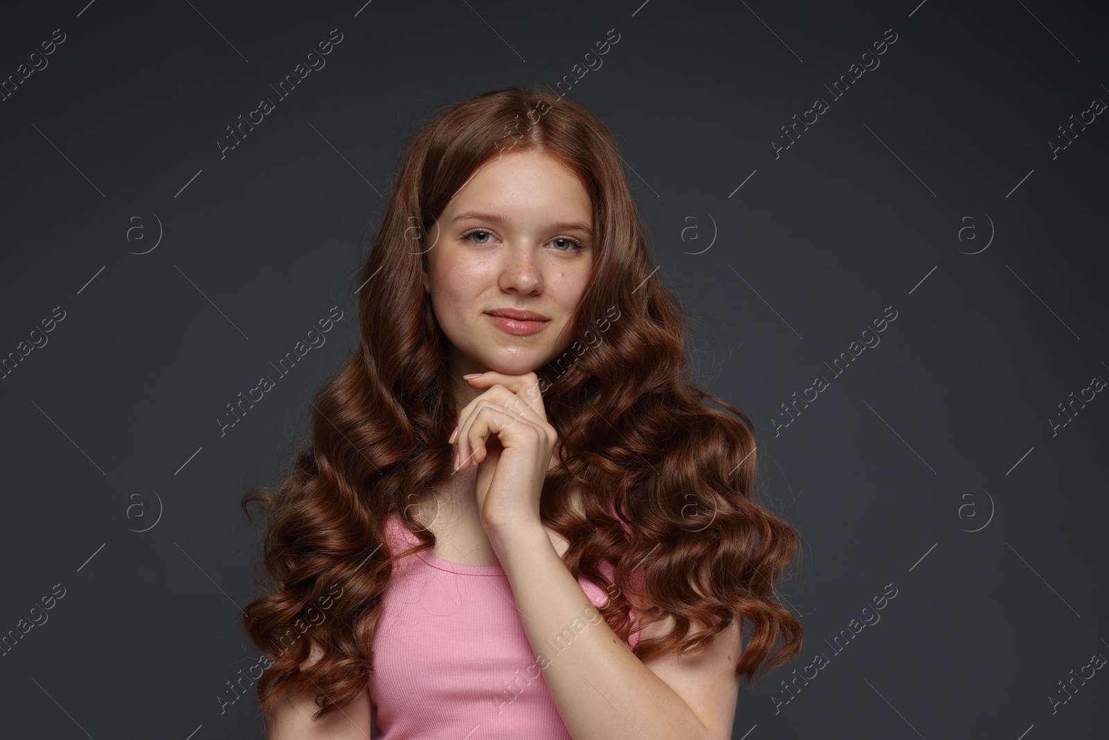 Portrait of beautiful teenage girl with healthy wavy hair on dark grey background Photo of Portrait of beautiful teenage girl with healthy wavy hair on dark grey background