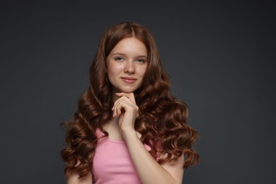 Photo of Portrait of beautiful teenage girl with healthy wavy hair on dark grey background