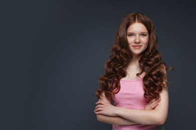 Photo of Portrait of beautiful teenage girl with healthy wavy hair on dark grey background. Space for text