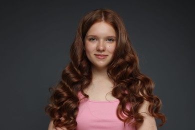 Photo of Portrait of beautiful teenage girl with healthy wavy hair on dark grey background