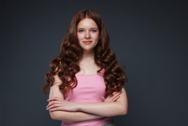 Photo of Portrait of beautiful teenage girl with healthy wavy hair on dark grey background