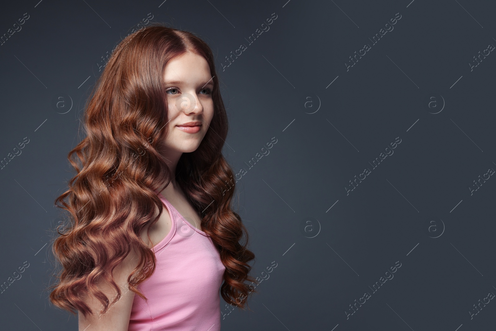 Beautiful teenage girl with healthy wavy hair on dark grey background. Space for text Photo of Beautiful teenage girl with healthy wavy hair on dark grey background. Space for text
