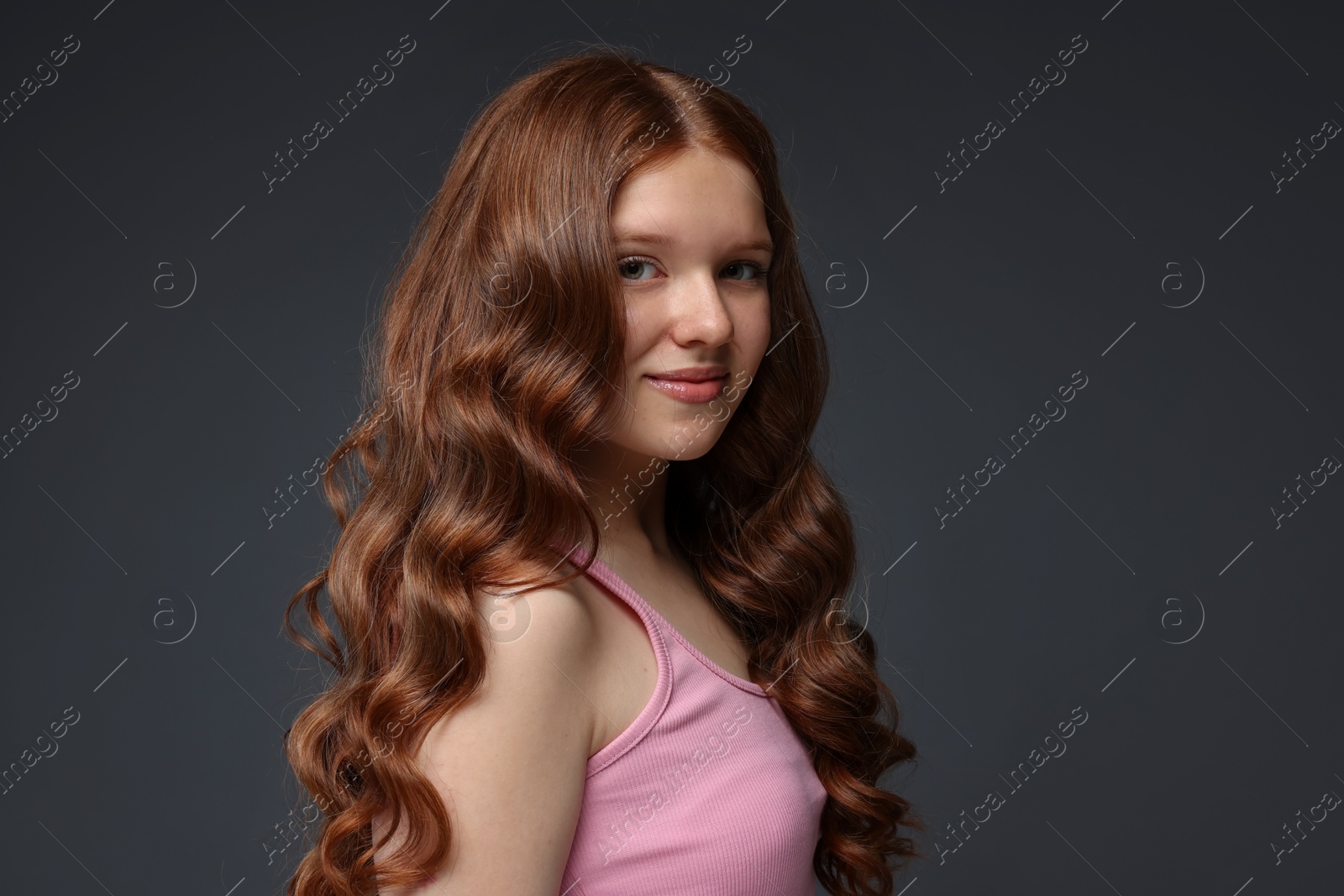 Portrait of beautiful teenage girl with healthy wavy hair on dark grey background Photo of Portrait of beautiful teenage girl with healthy wavy hair on dark grey background