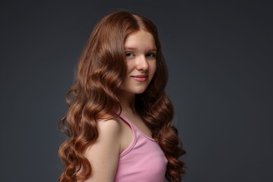 Photo of Portrait of beautiful teenage girl with healthy wavy hair on dark grey background