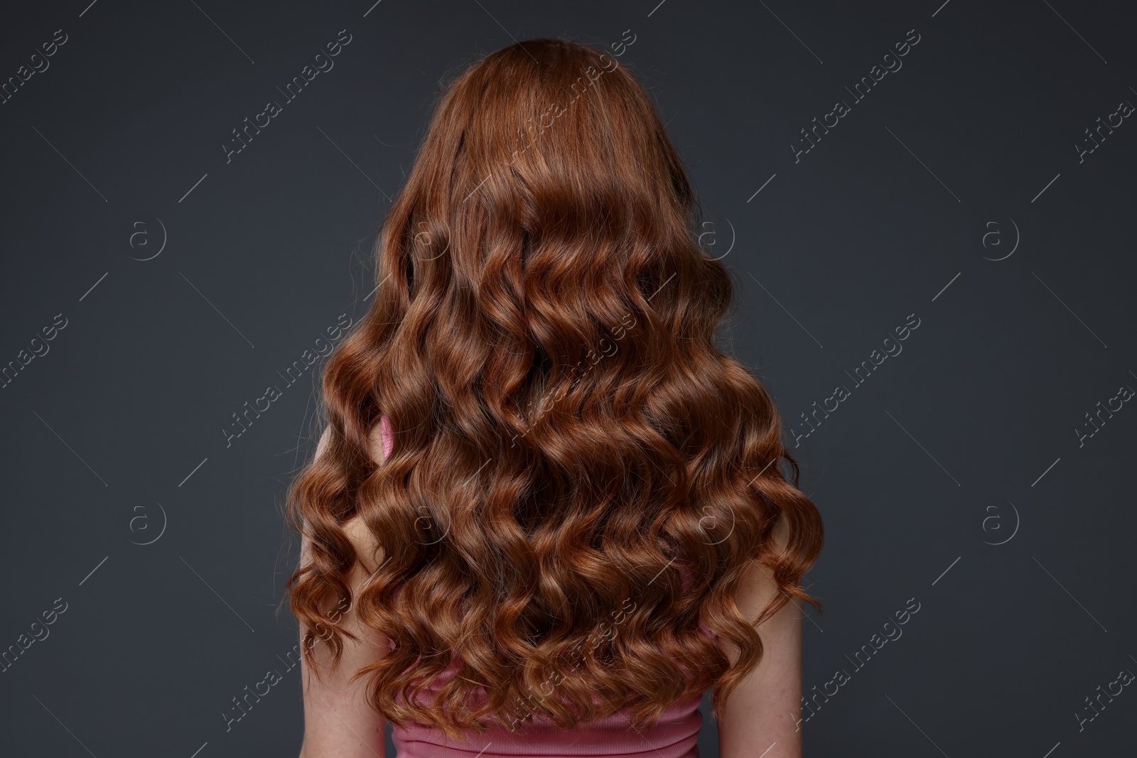 Teenage girl with healthy wavy hair on dark grey background, back view Photo of Teenage girl with healthy wavy hair on dark grey background, back view
