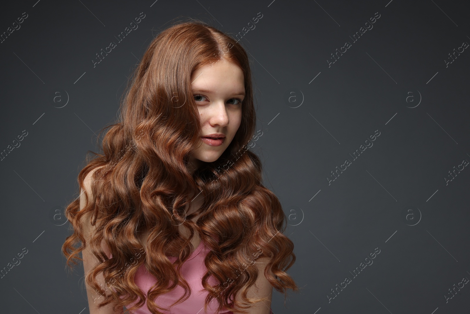 Portrait of beautiful teenage girl with healthy wavy hair on dark grey background. Space for text Photo of Portrait of beautiful teenage girl with healthy wavy hair on dark grey background. Space for text
