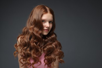 Photo of Portrait of beautiful teenage girl with healthy wavy hair on dark grey background. Space for text