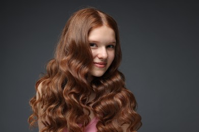 Photo of Portrait of beautiful teenage girl with healthy wavy hair on dark grey background