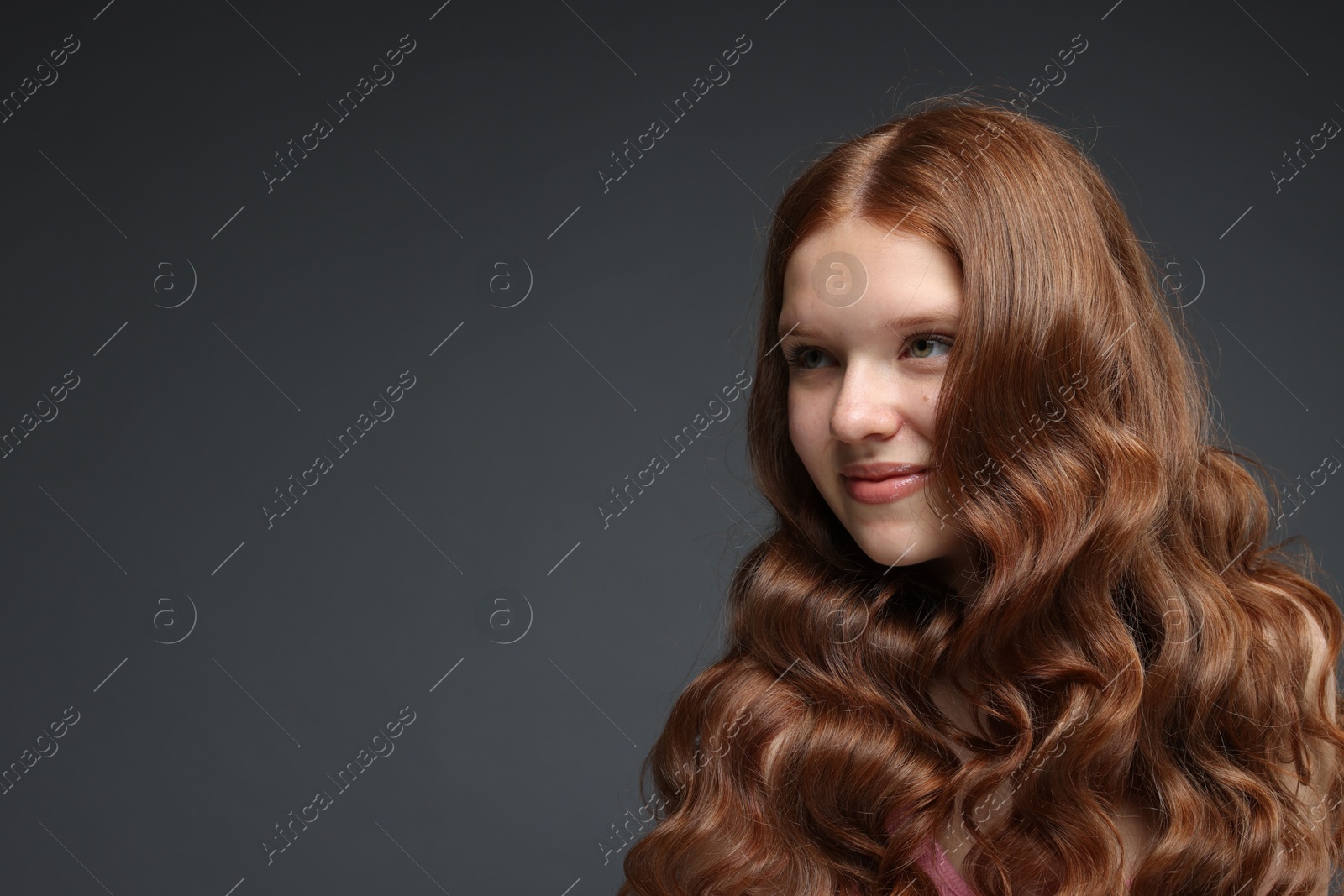 Beautiful teenage girl with healthy wavy hair on dark grey background. Space for text Photo of Beautiful teenage girl with healthy wavy hair on dark grey background. Space for text