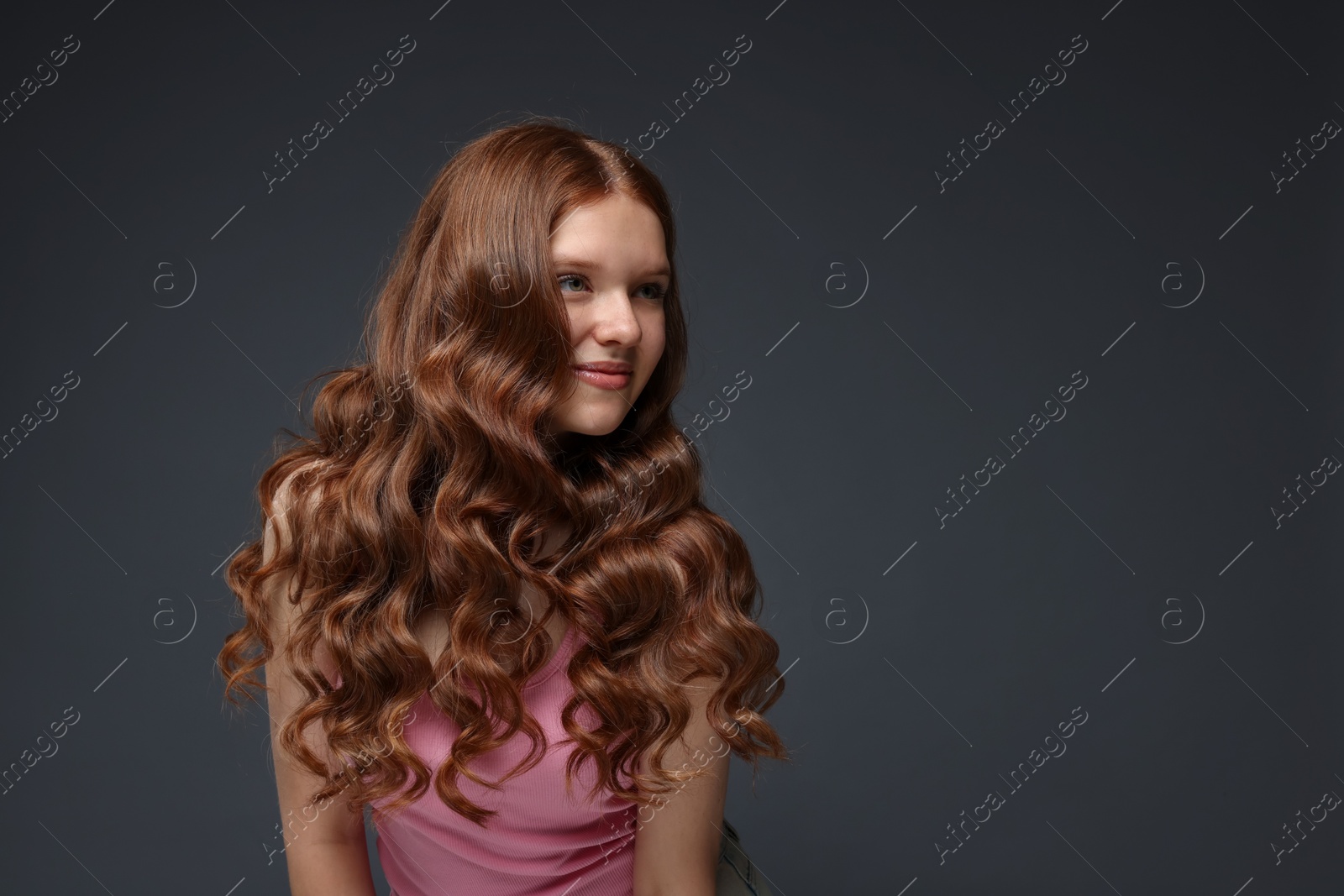 Beautiful teenage girl with healthy wavy hair on dark grey background. Space for text Photo of Beautiful teenage girl with healthy wavy hair on dark grey background. Space for text