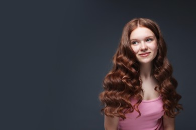 Photo of Beautiful teenage girl with healthy wavy hair on dark grey background. Space for text