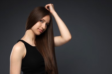 Photo of Portrait of beautiful teenage girl with healthy long hair on dark grey background. Space for text