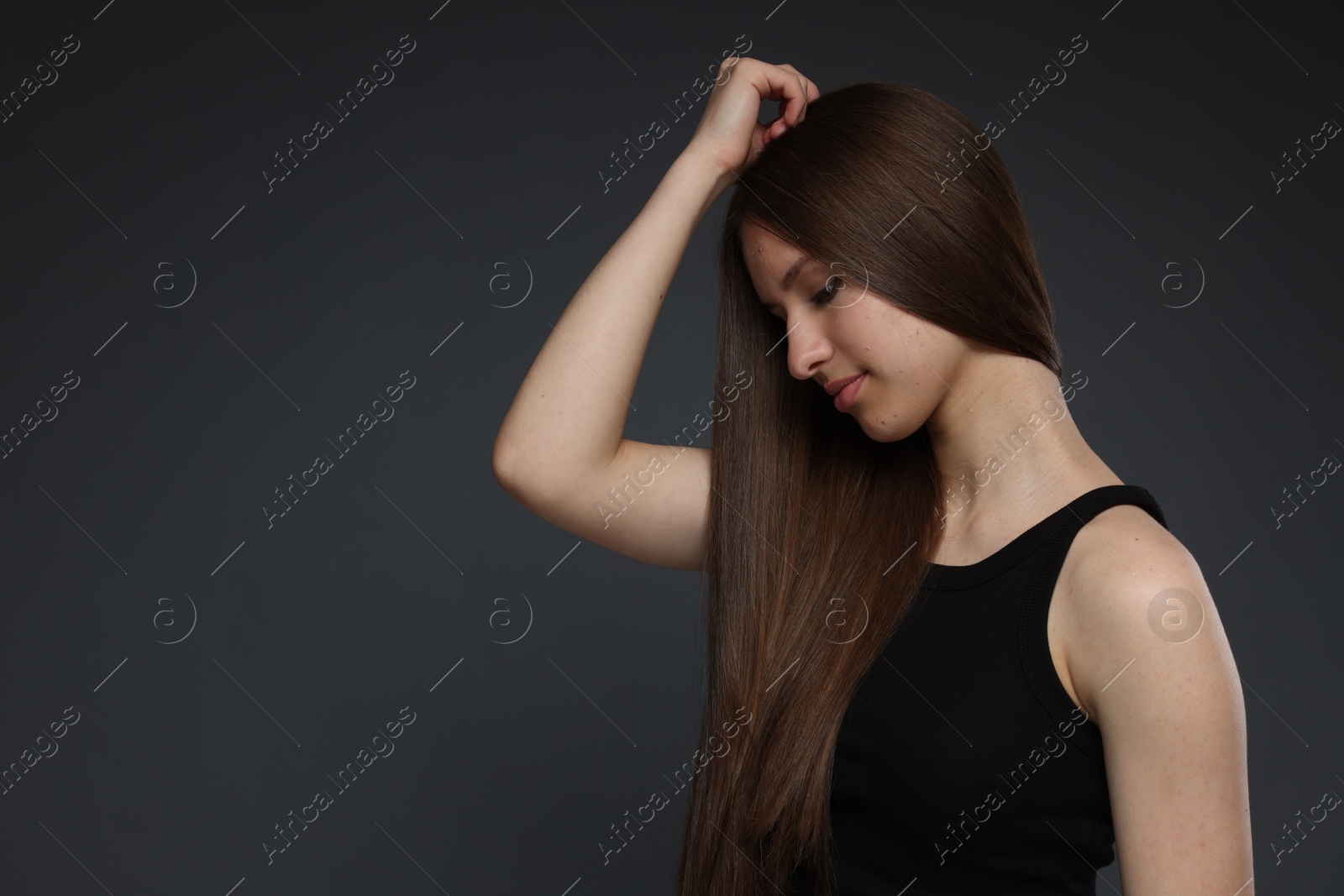 Beautiful teenage girl with healthy long hair on dark grey background. Space for text Photo of Beautiful teenage girl with healthy long hair on dark grey background. Space for text