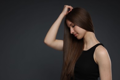 Photo of Beautiful teenage girl with healthy long hair on dark grey background. Space for text