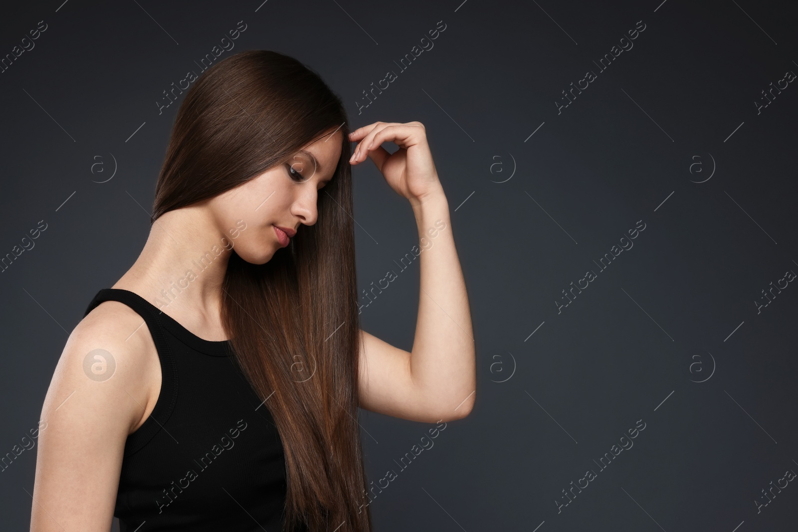 Beautiful teenage girl with healthy long hair on dark grey background. Space for text Photo of Beautiful teenage girl with healthy long hair on dark grey background. Space for text