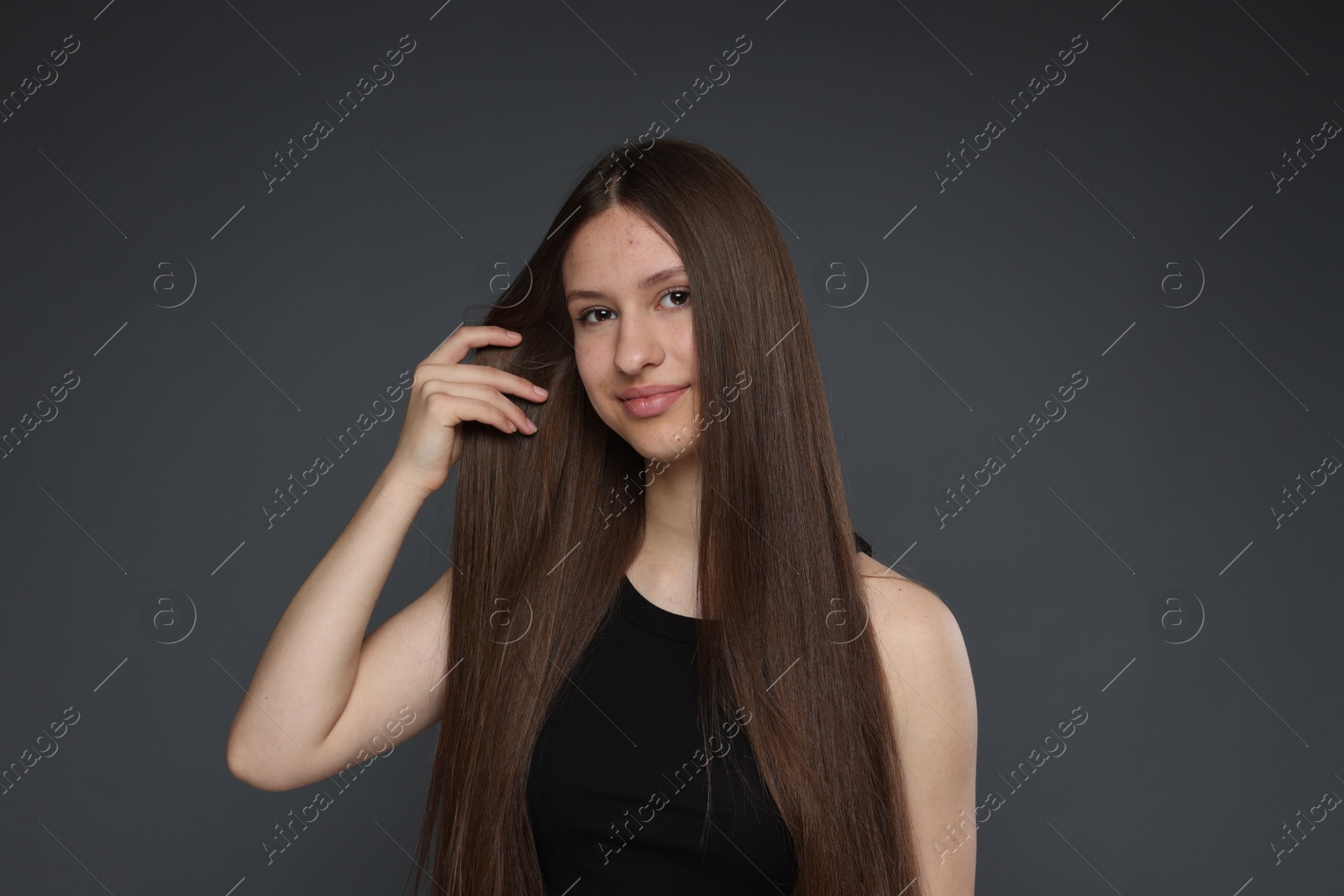 Portrait of beautiful teenage girl with healthy long hair on dark grey background Photo of Portrait of beautiful teenage girl with healthy long hair on dark grey background