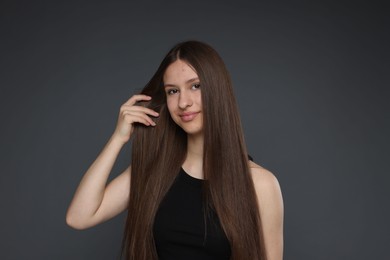 Photo of Portrait of beautiful teenage girl with healthy long hair on dark grey background