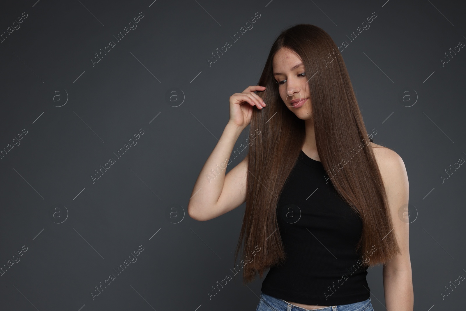 Beautiful teenage girl with healthy long hair on dark grey background. Space for text Photo of Beautiful teenage girl with healthy long hair on dark grey background. Space for text