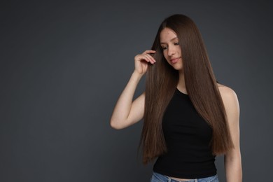 Photo of Beautiful teenage girl with healthy long hair on dark grey background. Space for text
