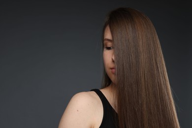 Photo of Teenage girl with healthy long hair on dark grey background. Space for text