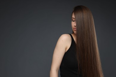Photo of Teenage girl with healthy long hair on dark grey background. Space for text