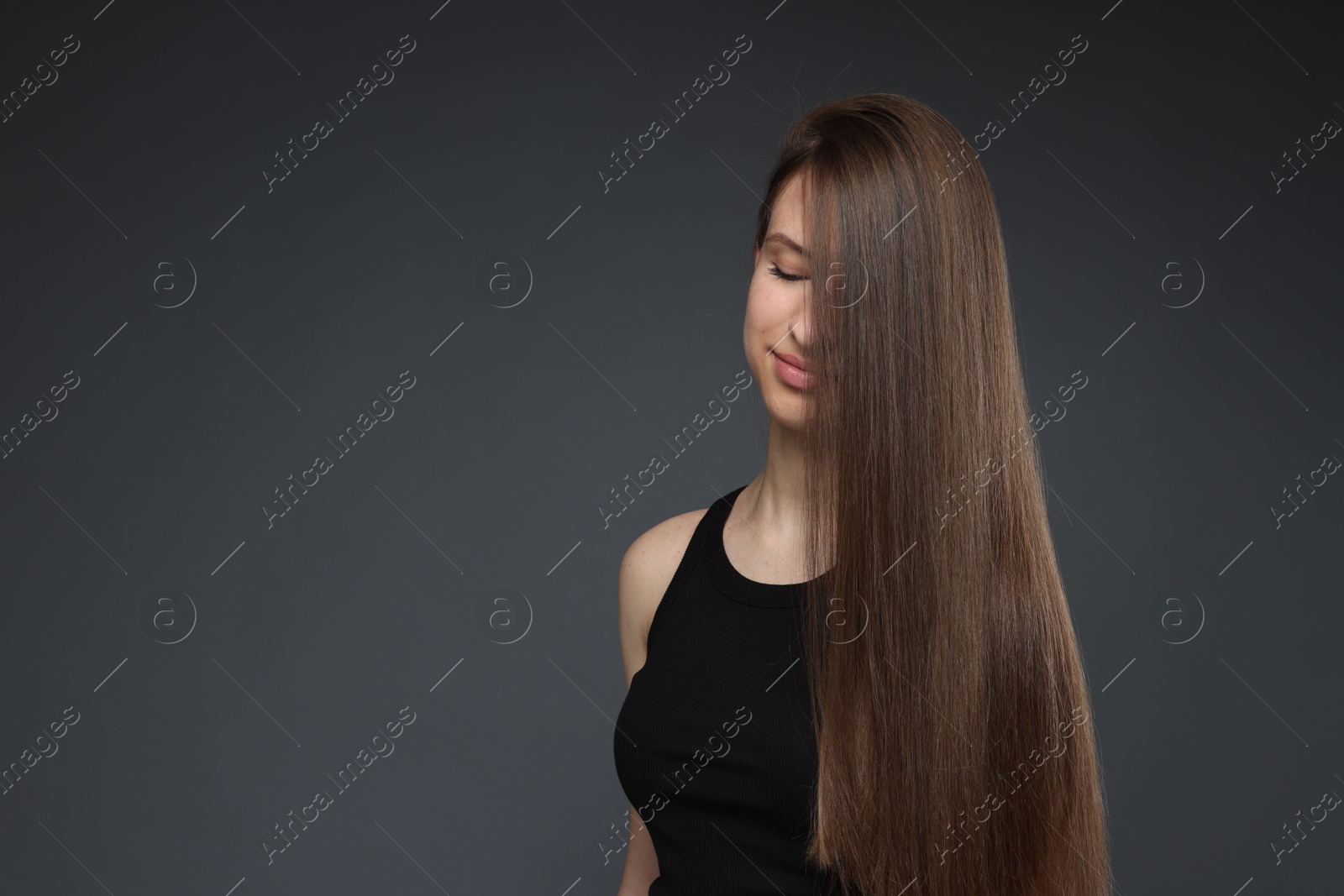 Teenage girl with healthy long hair on dark grey background. Space for text Photo of Teenage girl with healthy long hair on dark grey background. Space for text
