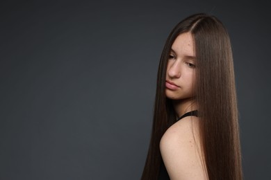 Photo of Beautiful teenage girl with healthy long hair on dark grey background. Space for text