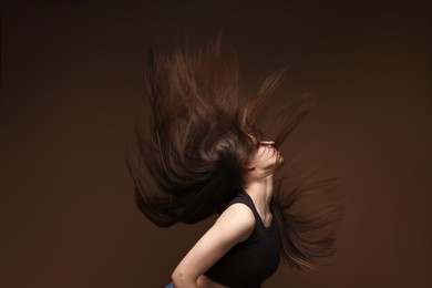 Photo of Teenage girl with healthy long hair on brown background
