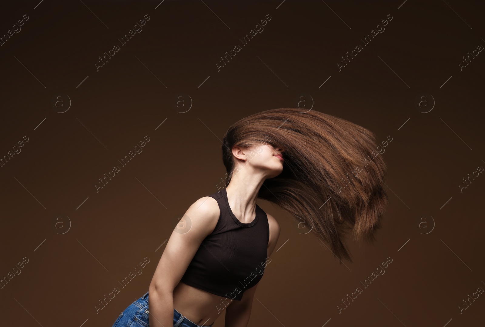 Teenage girl with healthy long hair on brown background Photo of Teenage girl with healthy long hair on brown background