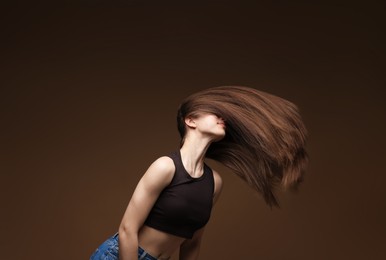 Photo of Teenage girl with healthy long hair on brown background