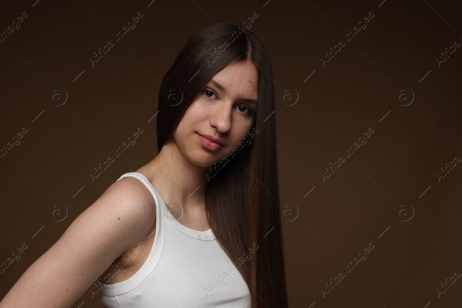 Portrait of beautiful teenage girl with healthy long hair on brown background Photo of Portrait of beautiful teenage girl with healthy long hair on brown background