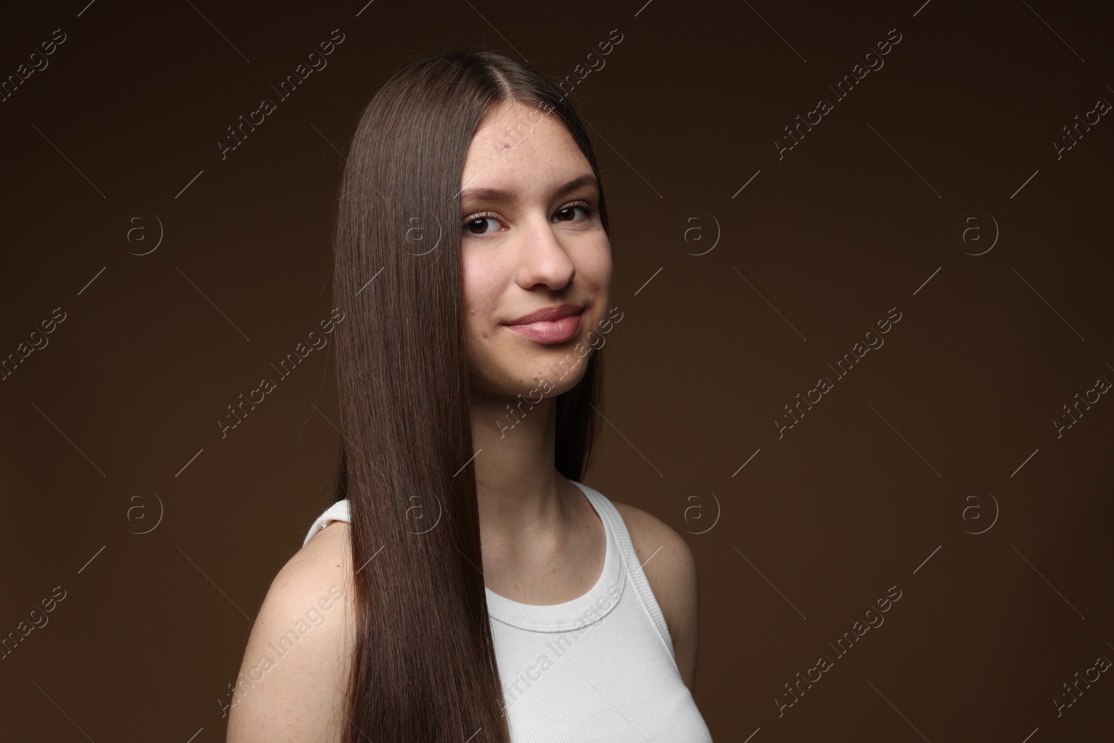 Portrait of beautiful teenage girl with healthy long hair on brown background Photo of Portrait of beautiful teenage girl with healthy long hair on brown background