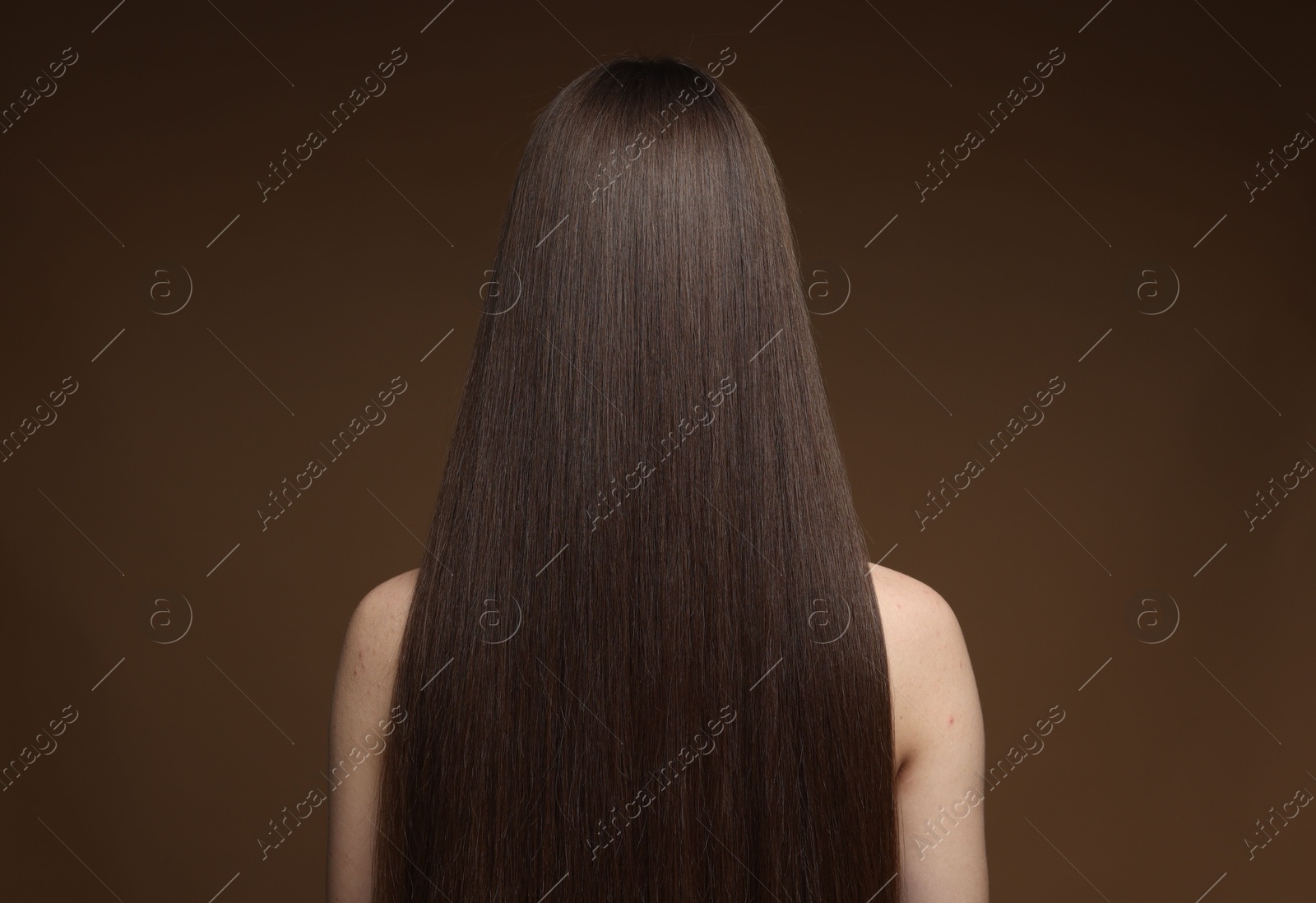 Teenage girl with healthy long hair on brown background, back view Photo of Teenage girl with healthy long hair on brown background, back view
