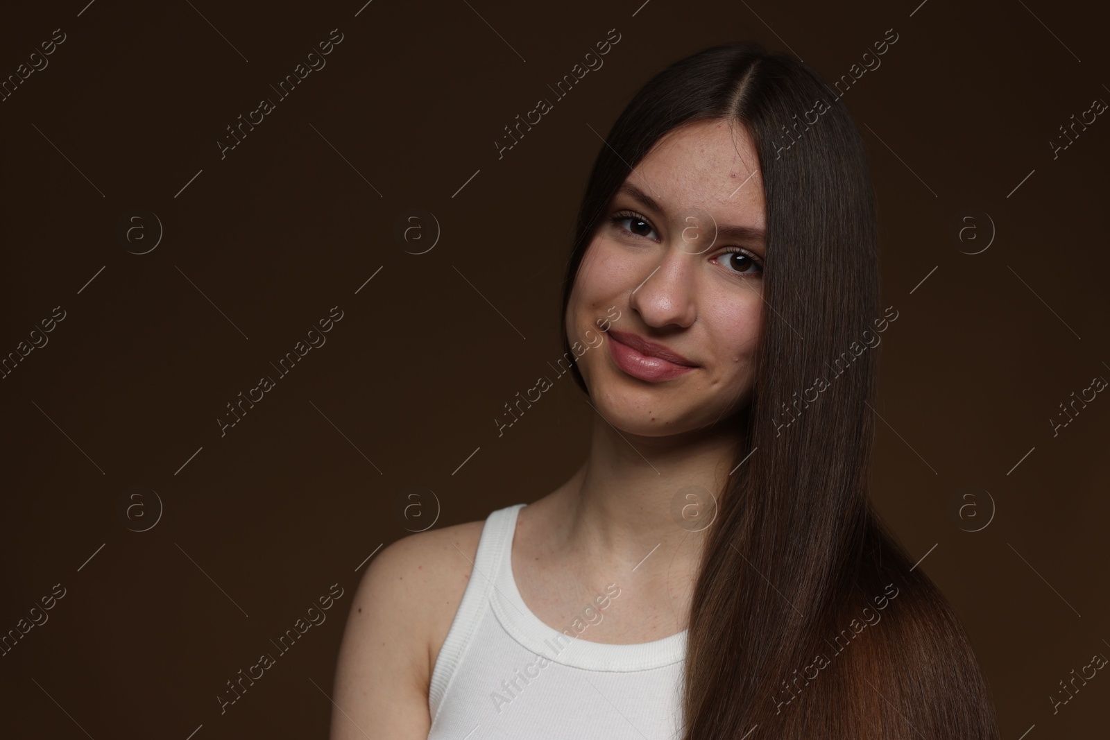 Portrait of beautiful teenage girl with healthy long hair on brown background. Space for text Photo of Portrait of beautiful teenage girl with healthy long hair on brown background. Space for text