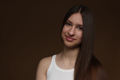 Photo of Portrait of beautiful teenage girl with healthy long hair on brown background. Space for text