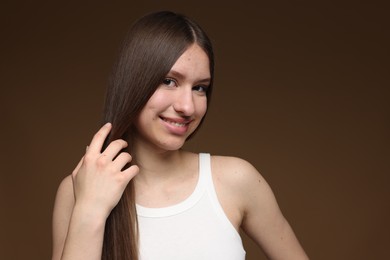 Photo of Portrait of smiling teenage girl with healthy long hair on brown background