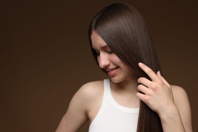 Photo of Smiling teenage girl with healthy long hair on brown background. Space for text