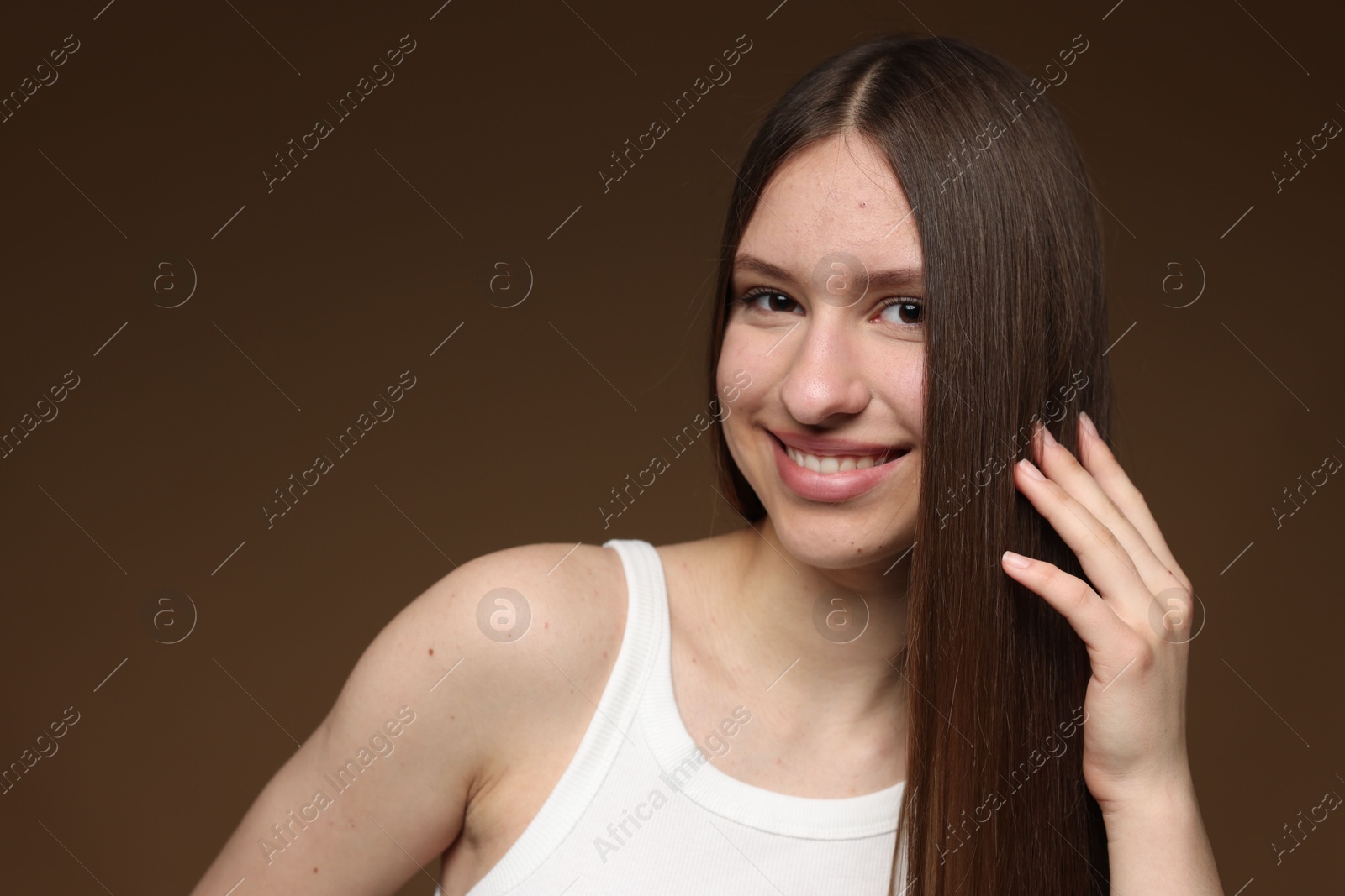 Portrait of smiling teenage girl with healthy long hair on brown background Photo of Portrait of smiling teenage girl with healthy long hair on brown background