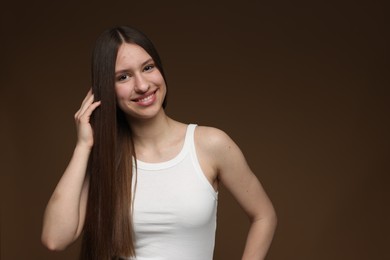 Photo of Portrait of smiling teenage girl with healthy long hair on brown background. Space for text