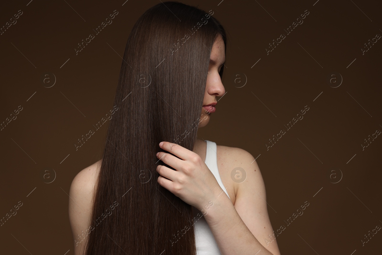 Teenage girl with healthy long hair on brown background Photo of Teenage girl with healthy long hair on brown background