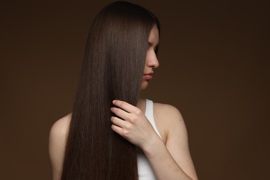 Photo of Teenage girl with healthy long hair on brown background