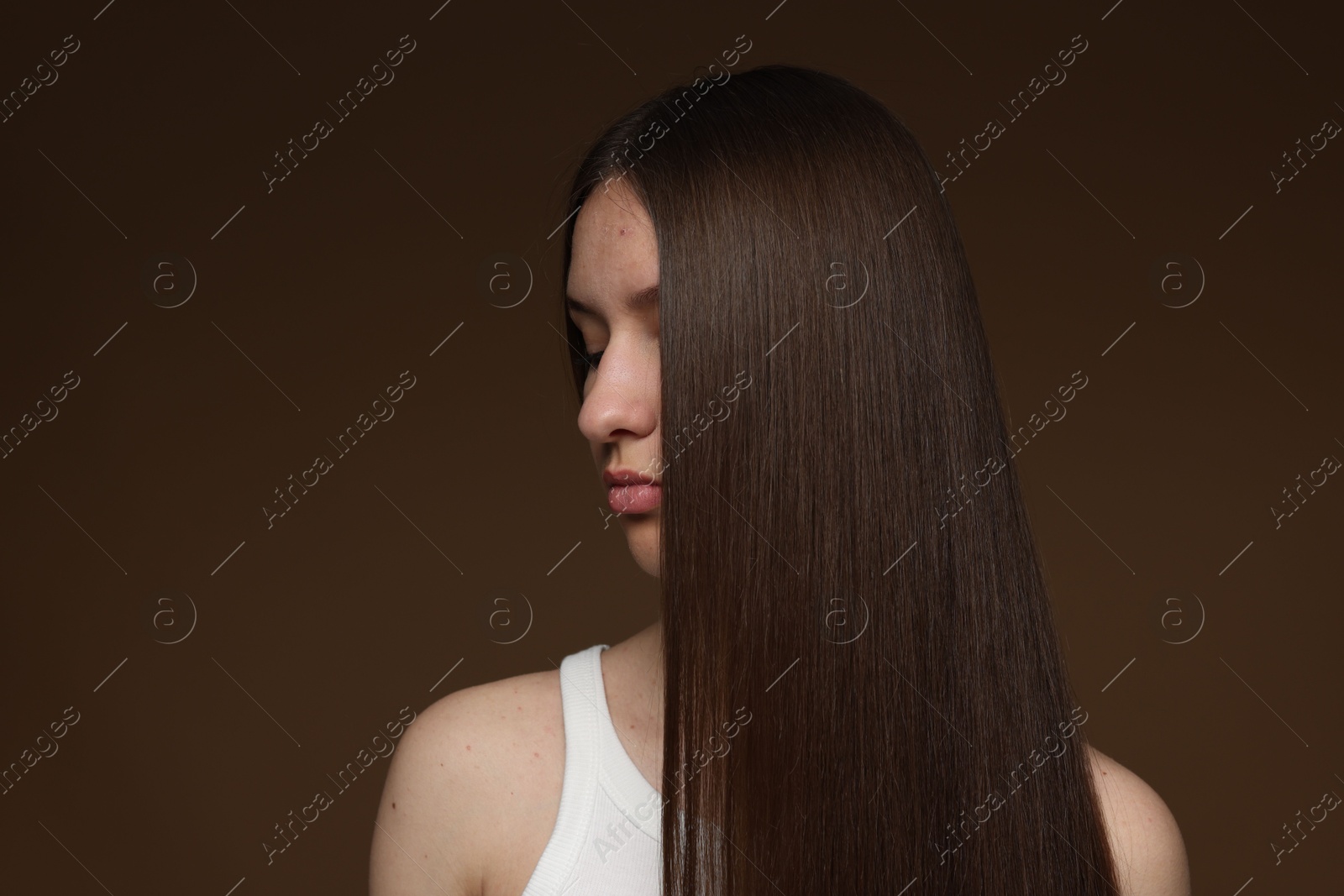 Teenage girl with healthy long hair on brown background Photo of Teenage girl with healthy long hair on brown background