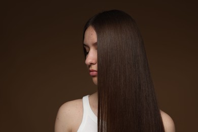 Photo of Teenage girl with healthy long hair on brown background