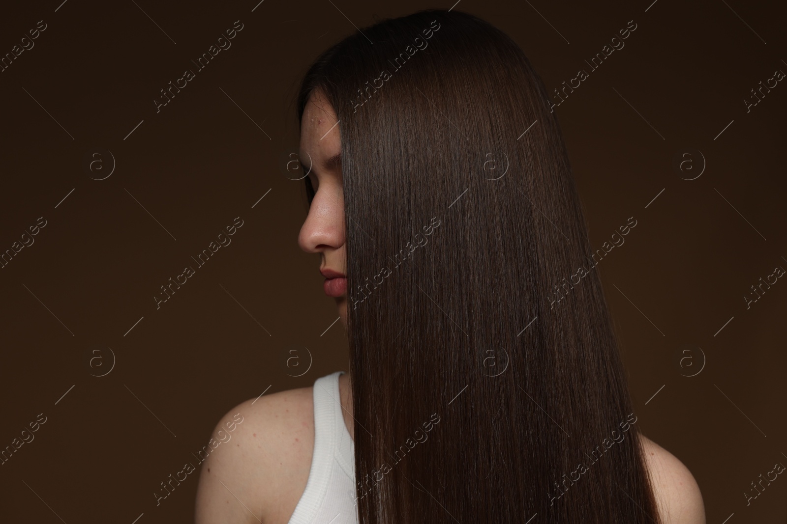 Teenage girl with healthy long hair on brown background Photo of Teenage girl with healthy long hair on brown background
