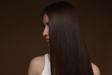 Photo of Teenage girl with healthy long hair on brown background