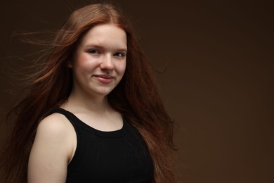 Photo of Portrait of beautiful teenage girl with healthy wavy hair on brown background. Space for text