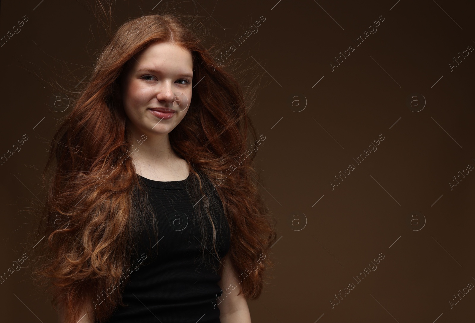 Portrait of beautiful teenage girl with healthy wavy hair on brown background. Space for text Photo of Portrait of beautiful teenage girl with healthy wavy hair on brown background. Space for text